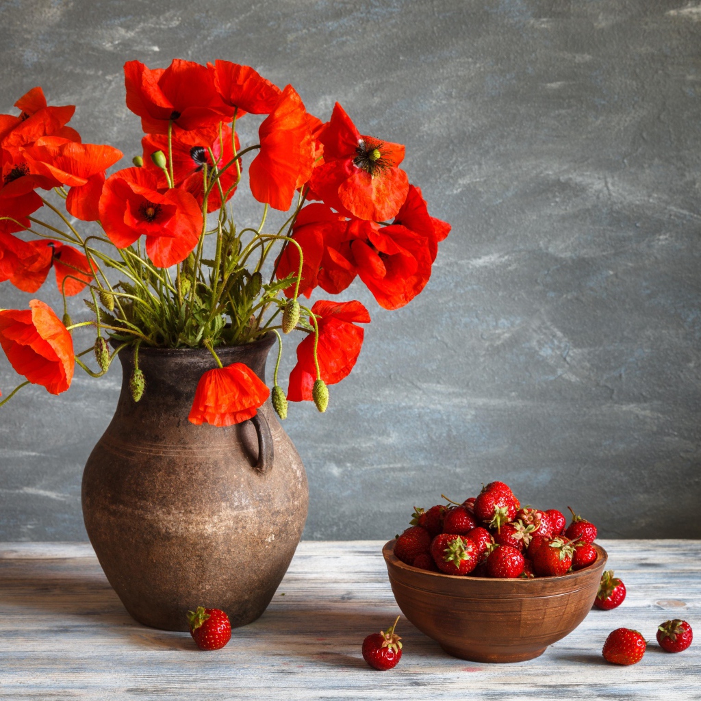 Красивый букет красных полевых маков в вазе на столе с клубникой