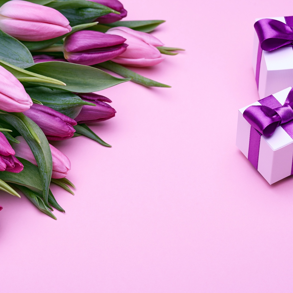 Букет фиолетовых тюльпанов с подарками на розовом фоне