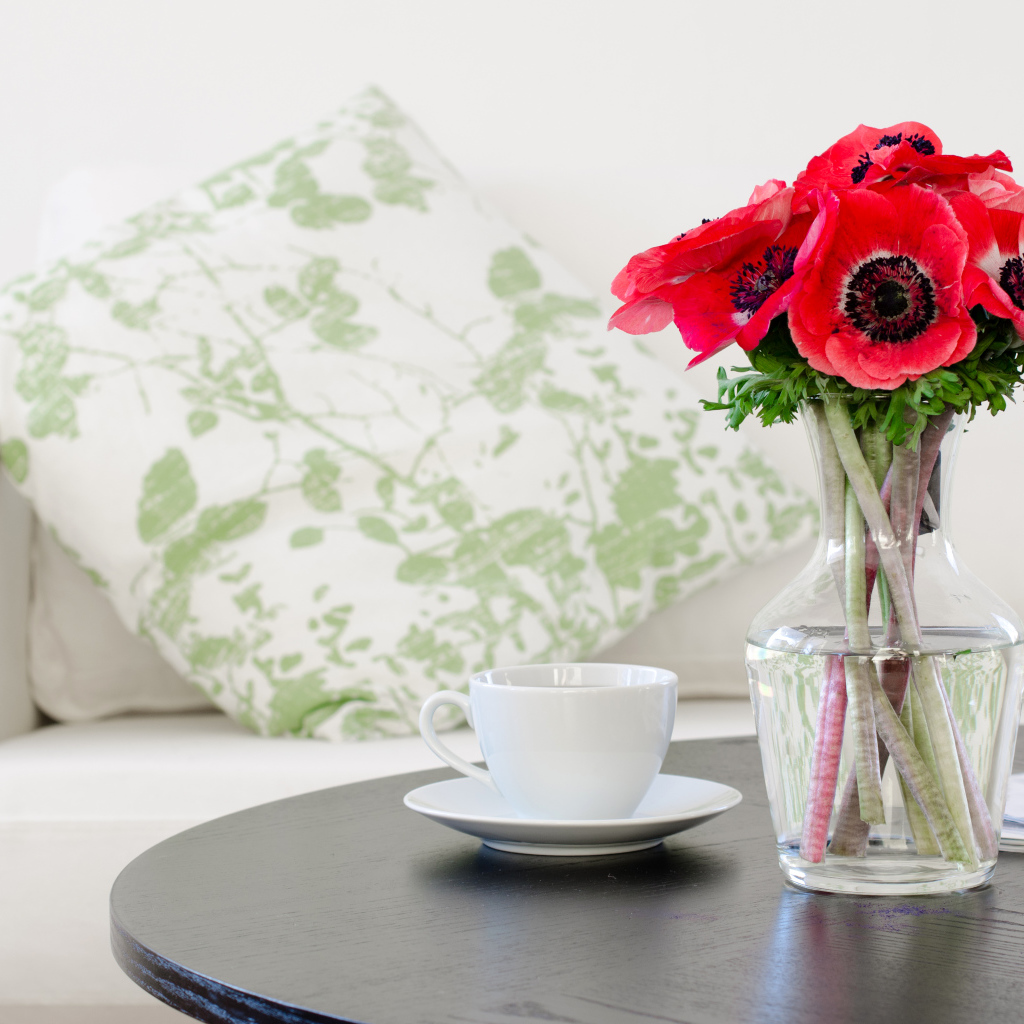 Букет красных цветов анемоны в вазе на столе с белой чашкой