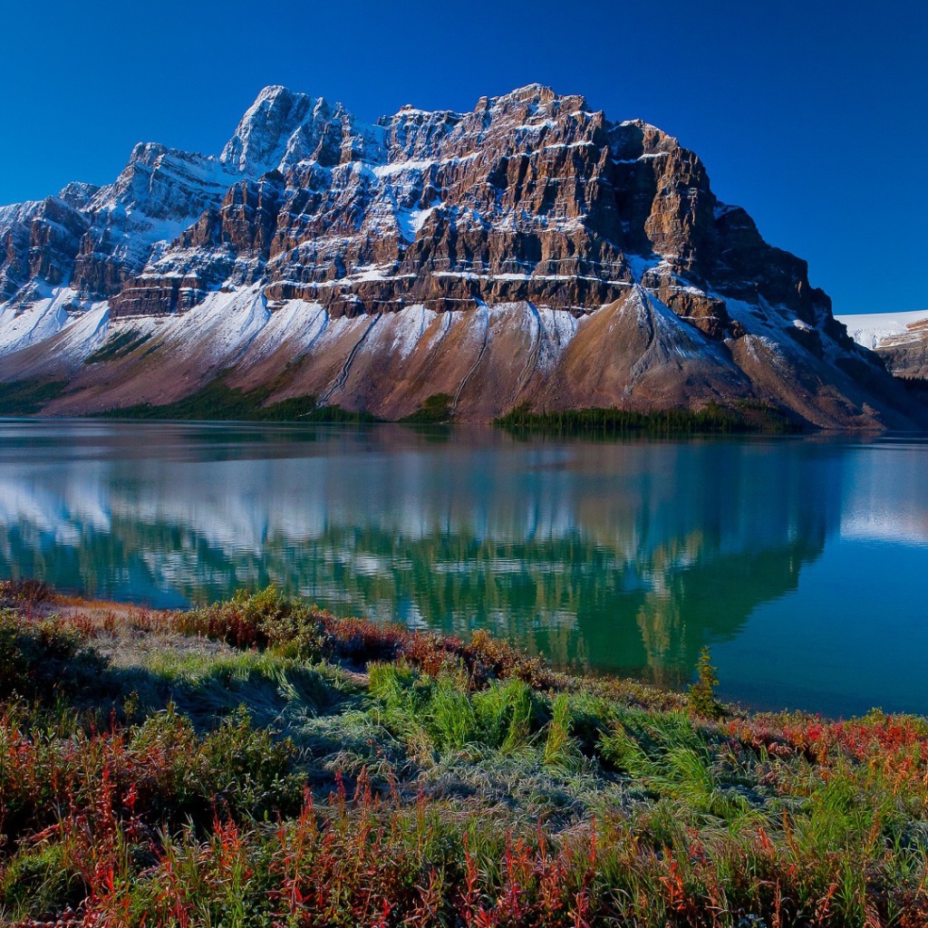 Заснеженные горы отражаются в голубой глади воды 
