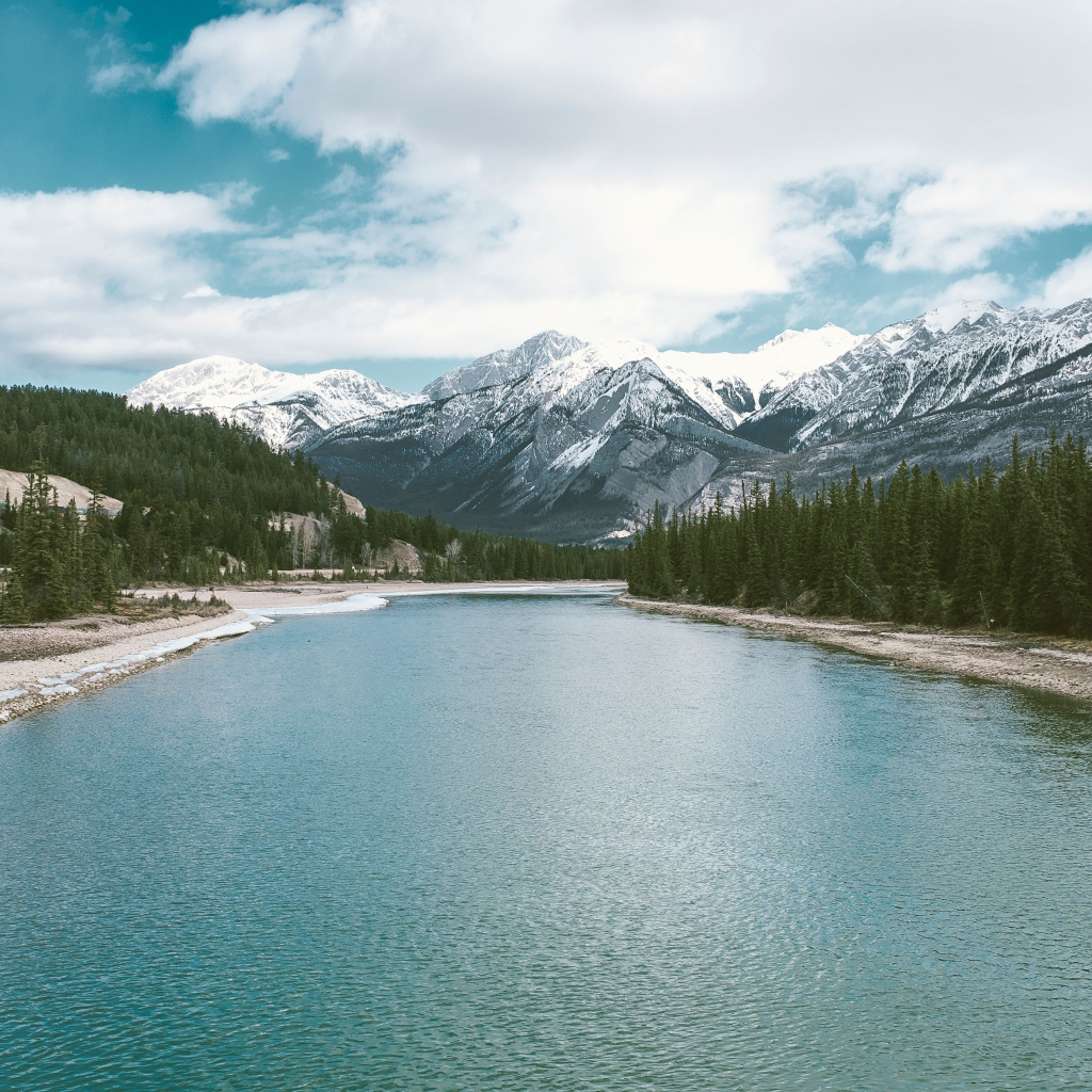 Чистая голубая вода в реке на фоне заснеженных гор 