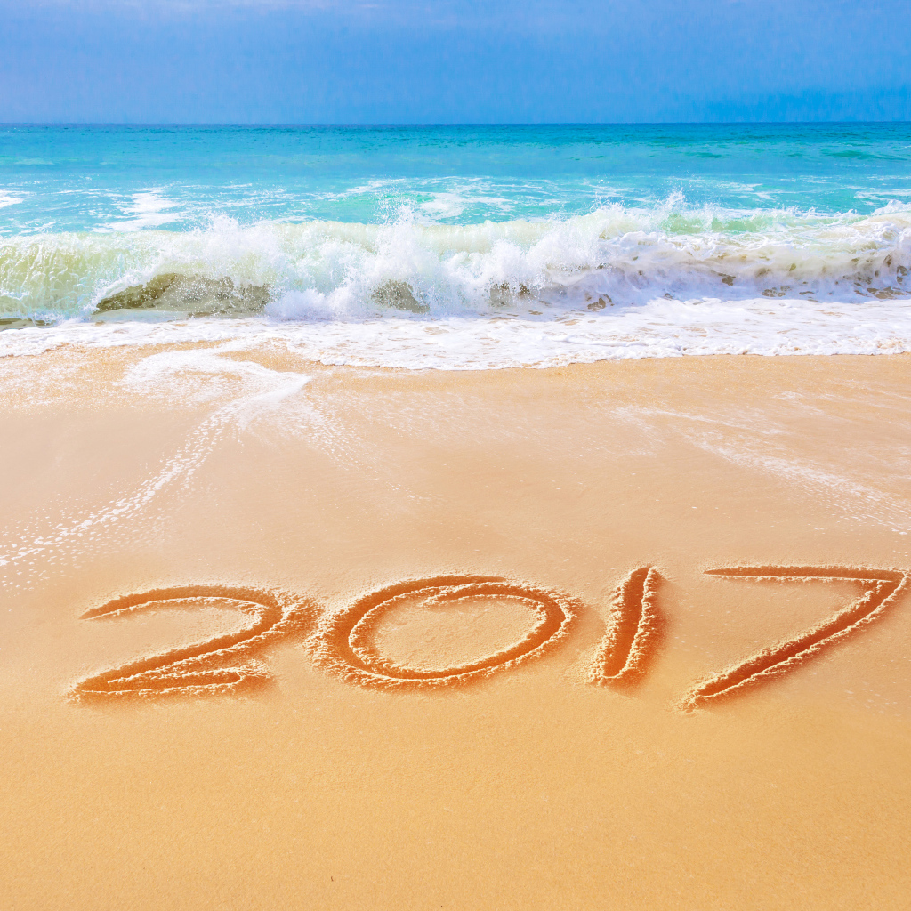 Надпись 2017 на песке у бушующего моря