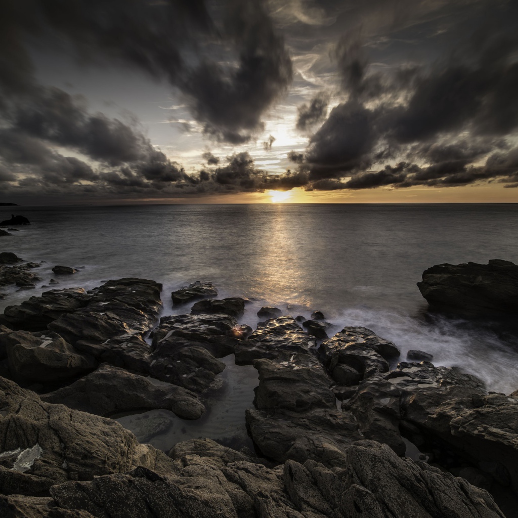 Низкие черные облака на закате в небе над океаном