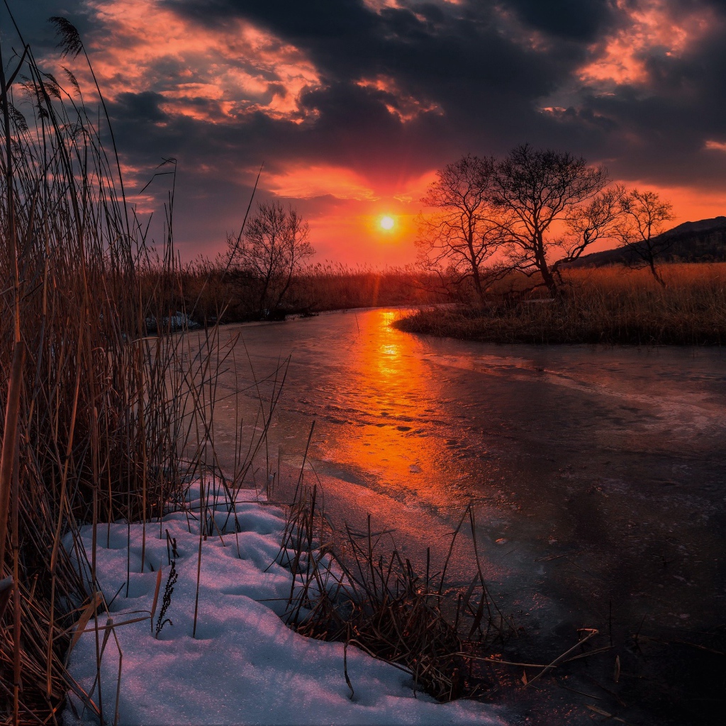 Закат солнца над покрытой льдом рекой