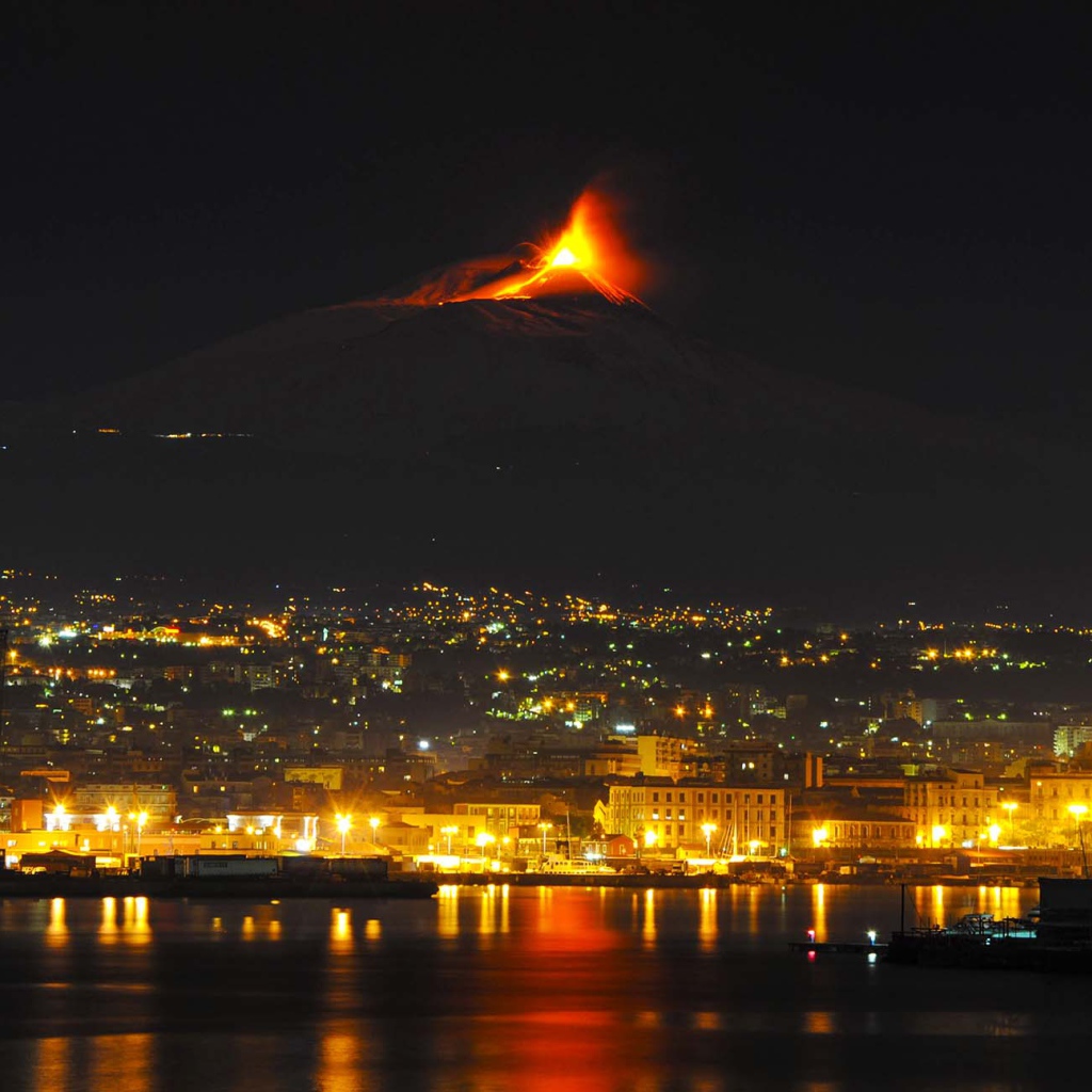 Пробуждение вулкана Этна на фоне ночного города 