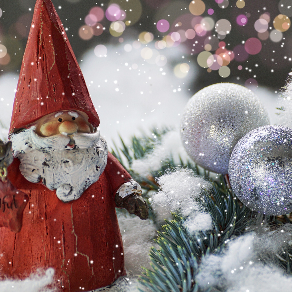 Статуэтка деда Мороза рядом с еловой веткой и яркими шарами
