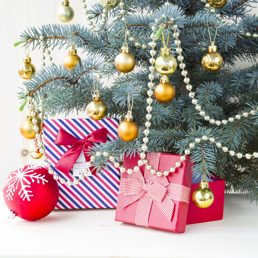 Подарки под зеленой наряженной елкой с золотыми шарами