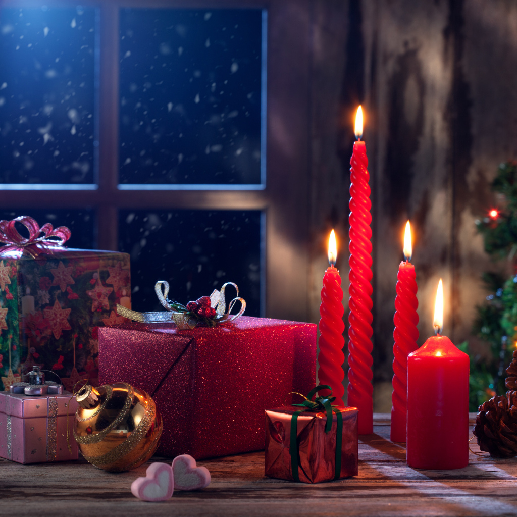 Зажженные красные свечи с подарками и игрушками на Новый год 2018
