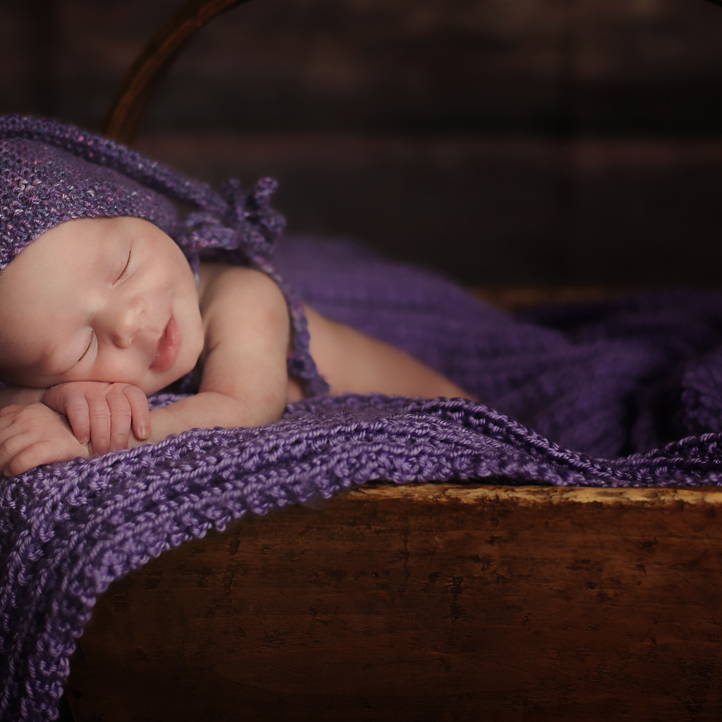 Грудной ребенок спит в деревянной корзине