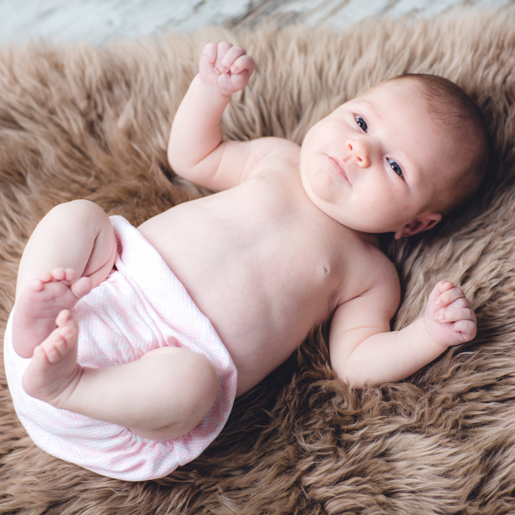 Грудной ребенок лежит на меховом покрывале