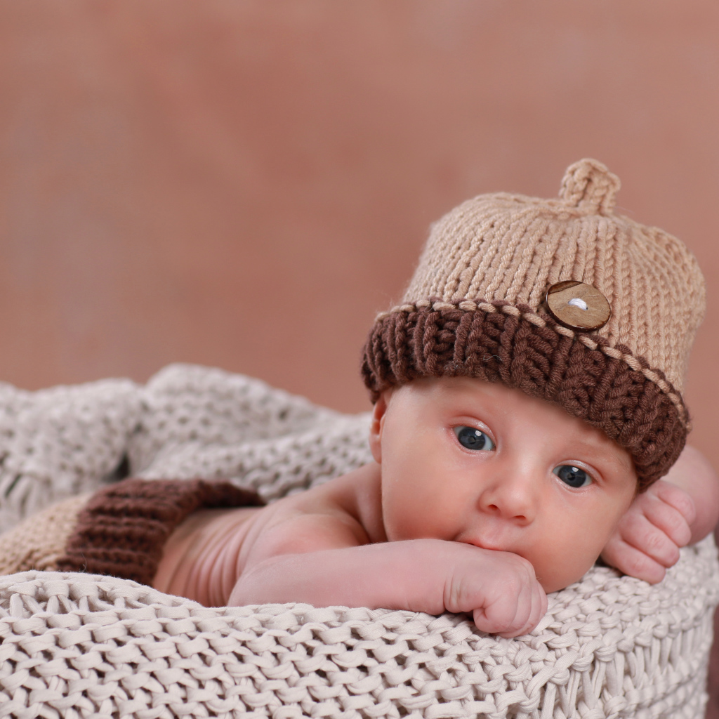 Грудной ребенок в вязаной коричневой шапке