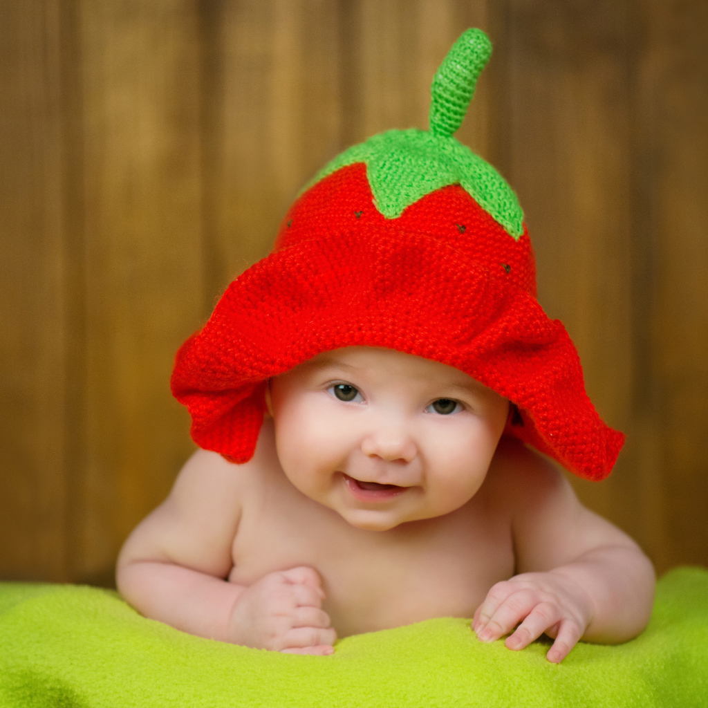 Младенец в забавной шапке клубнике на голове