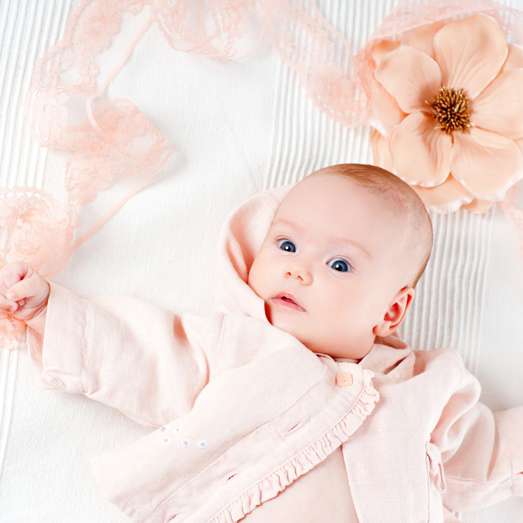 Младенец в розовом наряде с большим цветком у головы