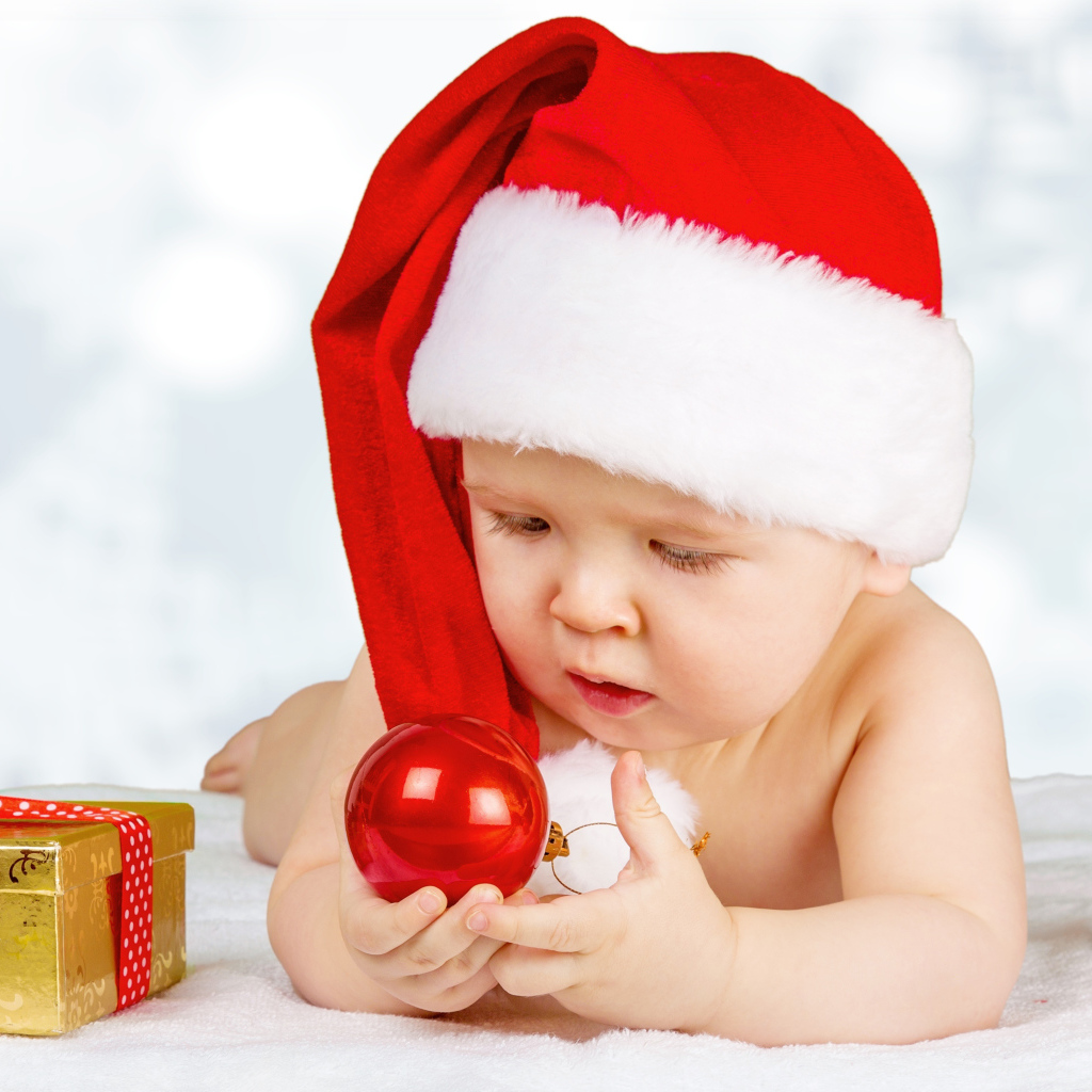 Младенец в красной новогодней шапке с елочными шарами на новый год