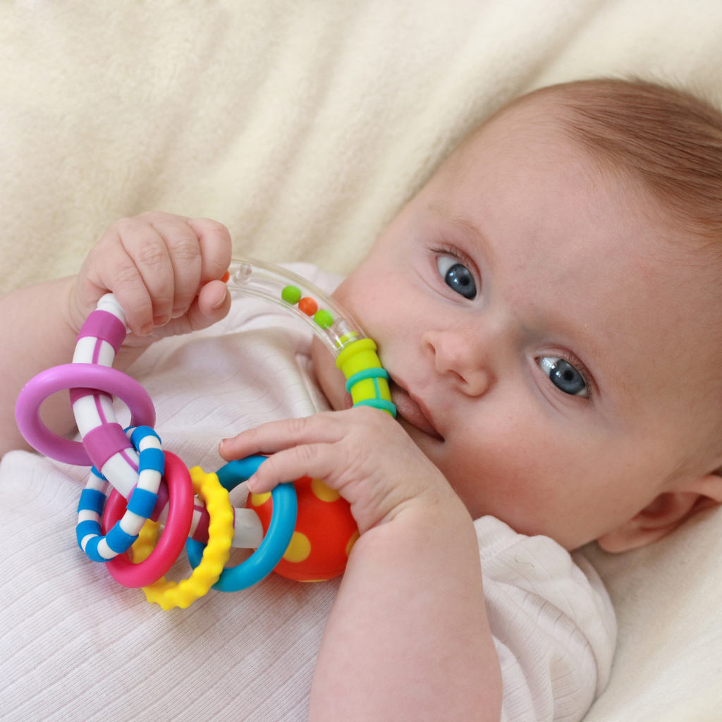 Грудной ребенок с погремушкой в руках