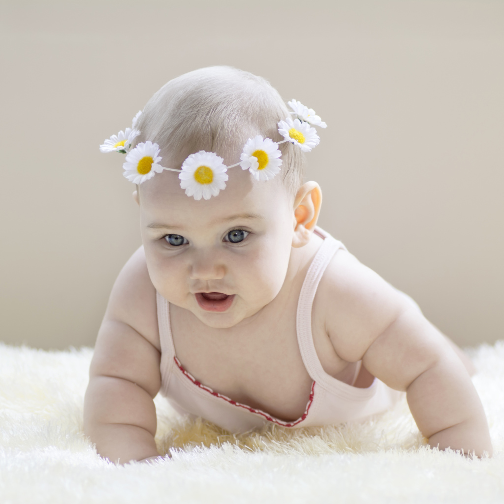 Грудной ребенок с венком из белых ромашек на голове