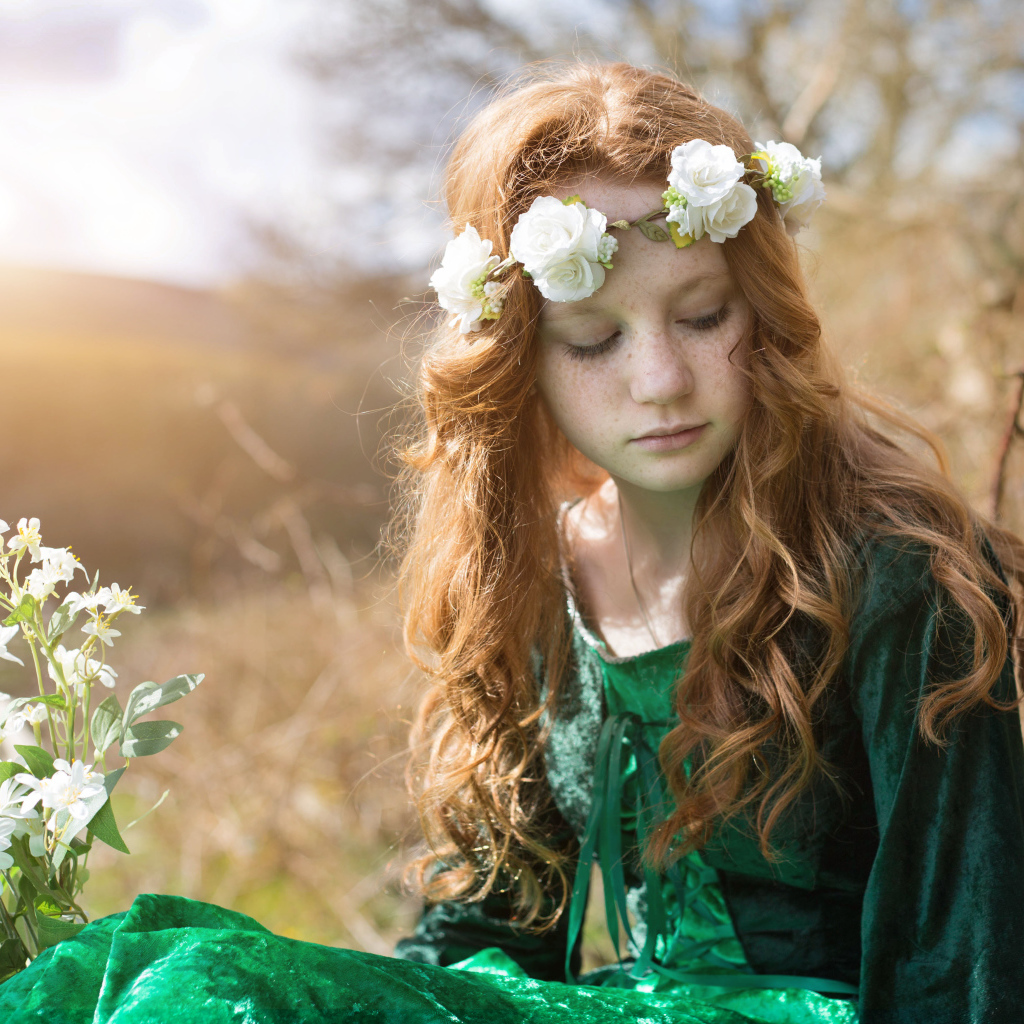 Милая рыжеволосая девочка в зеленом платье с венком на голове
