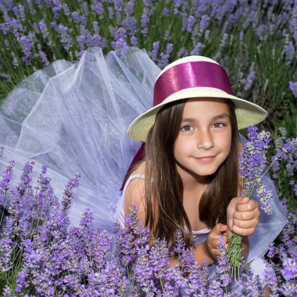 Девочка в шляпе лежит в фиолетовых цветах лаванды
