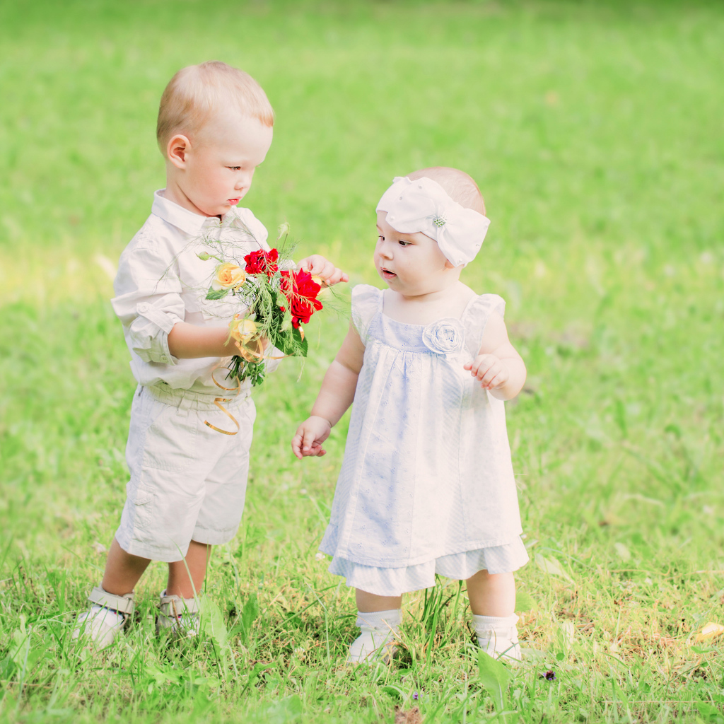 Маленький мальчик дарит букет полевых цветов девочке
