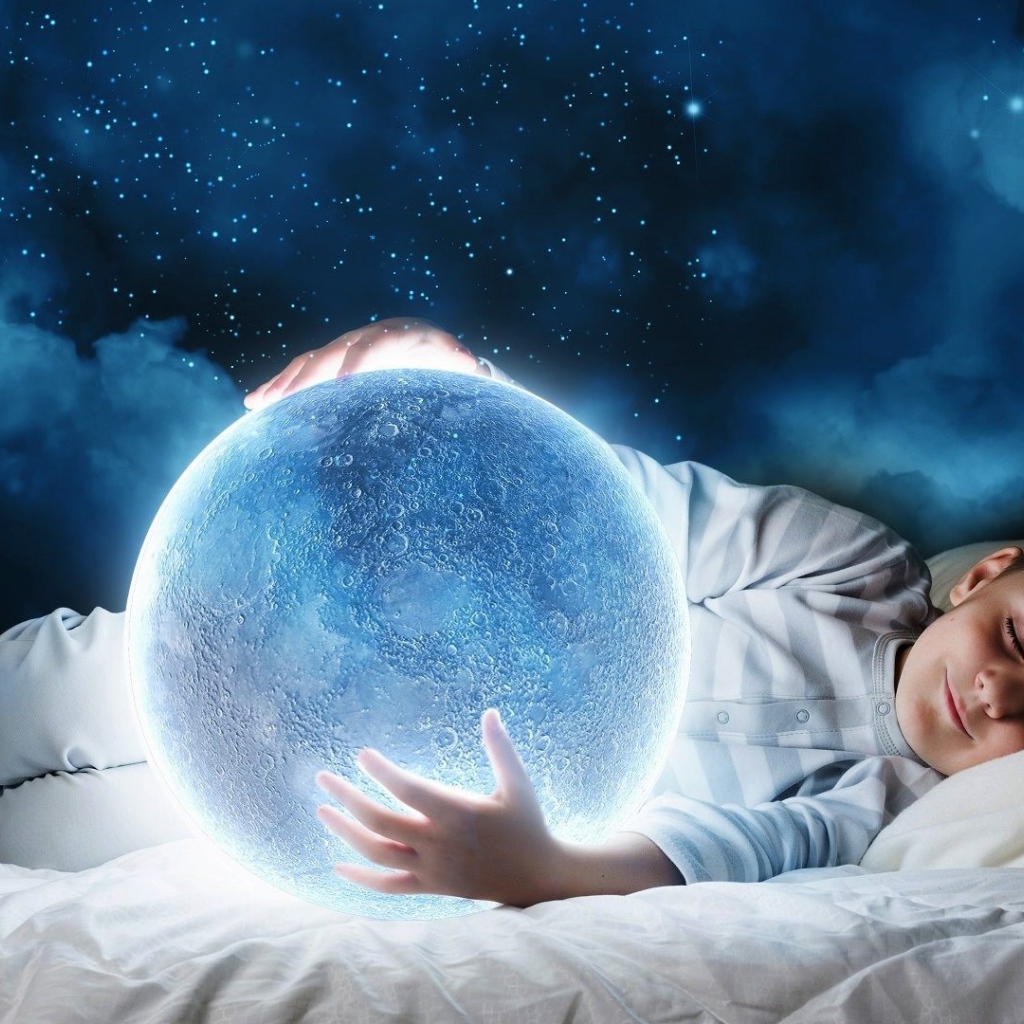 Маленький мальчик во сне держит в руках волшебную голубую луну