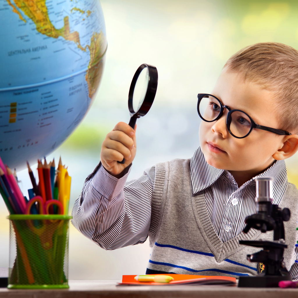 Маленький мальчик в очках исследует глобус