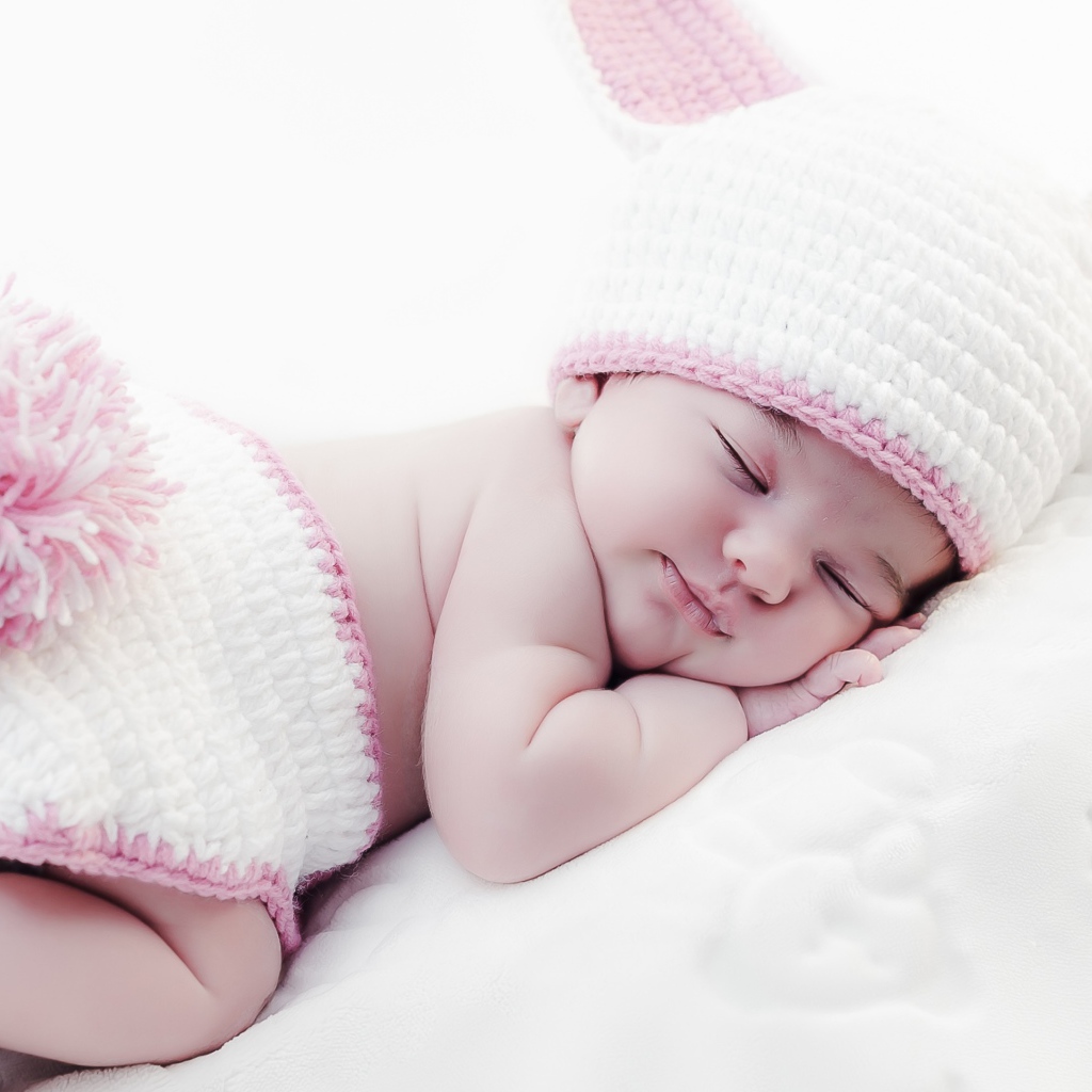 Маленький спящий ребенок в вязаном костюме зайчика