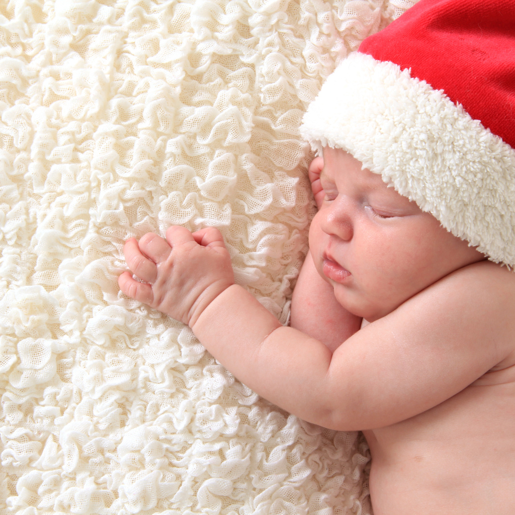Маленький спящий ребенок в красном новогоднем колпаке