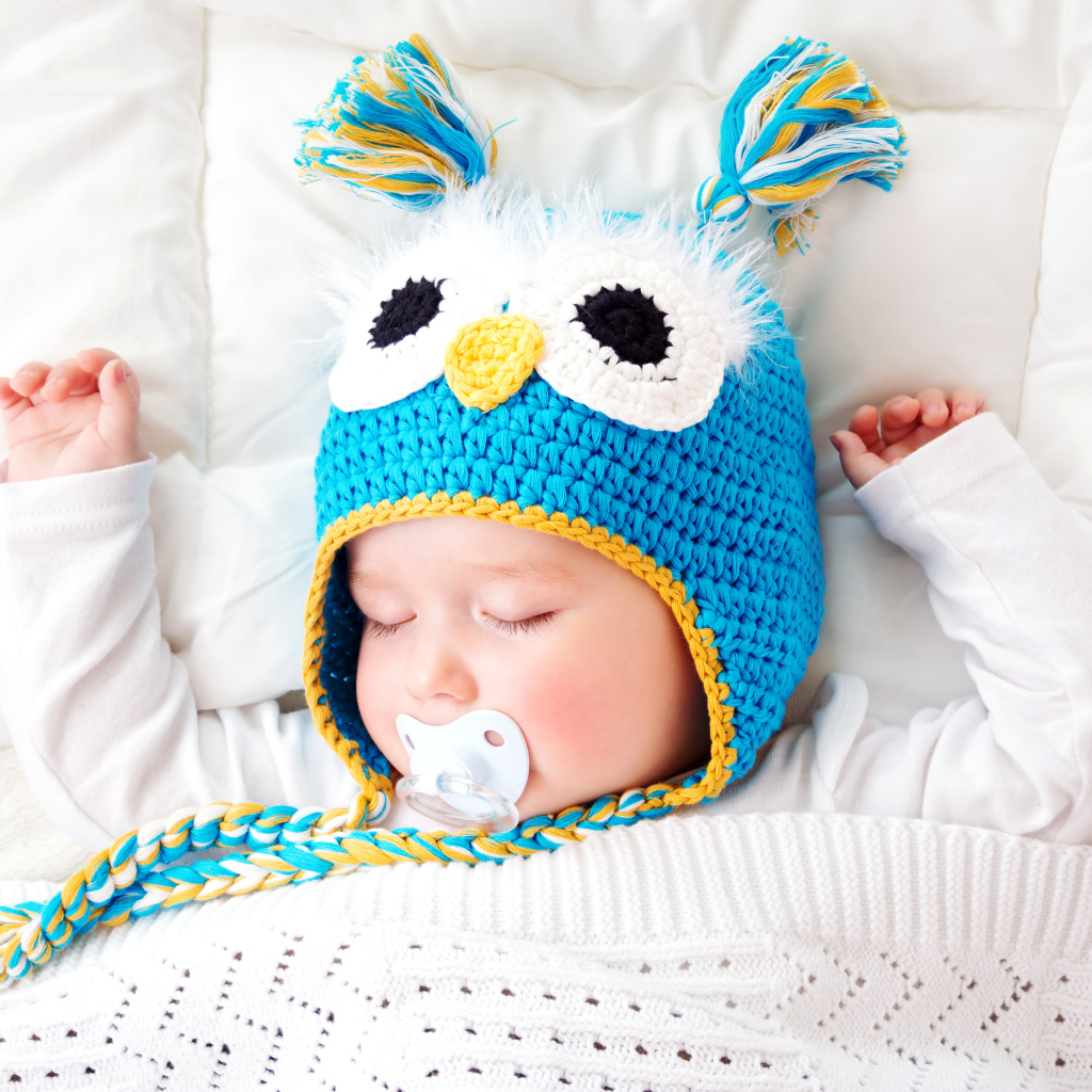 Спящий ребенок в забавной вязаной шапке