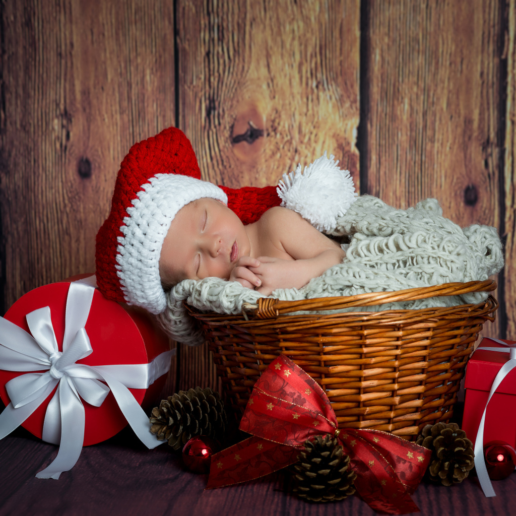 Маленький грудной ребенок спит в плетеной корзине с новогодними подарками
