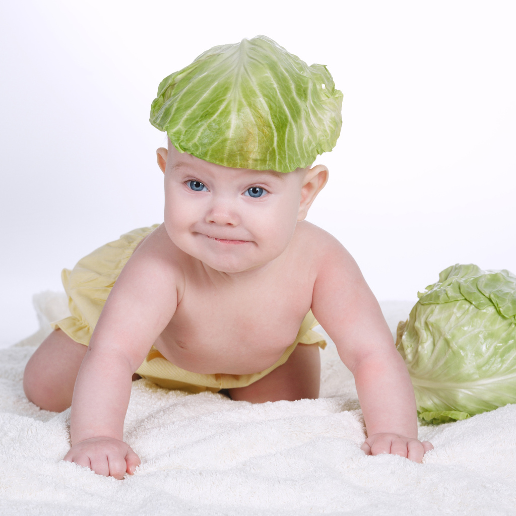 Маленький грудной ребенок с капустным листом на голове