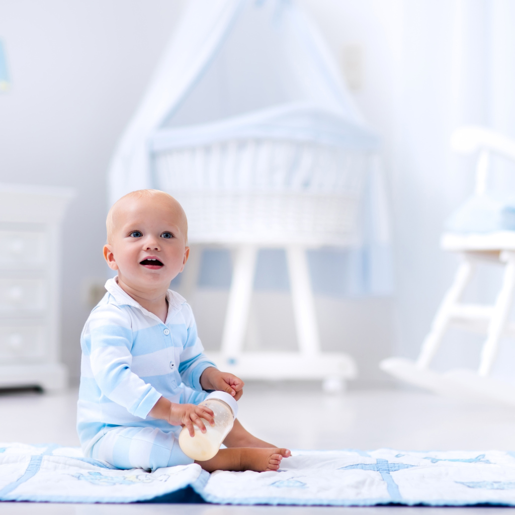 Маленький голубоглазый мальчик сидит на полу в комнате