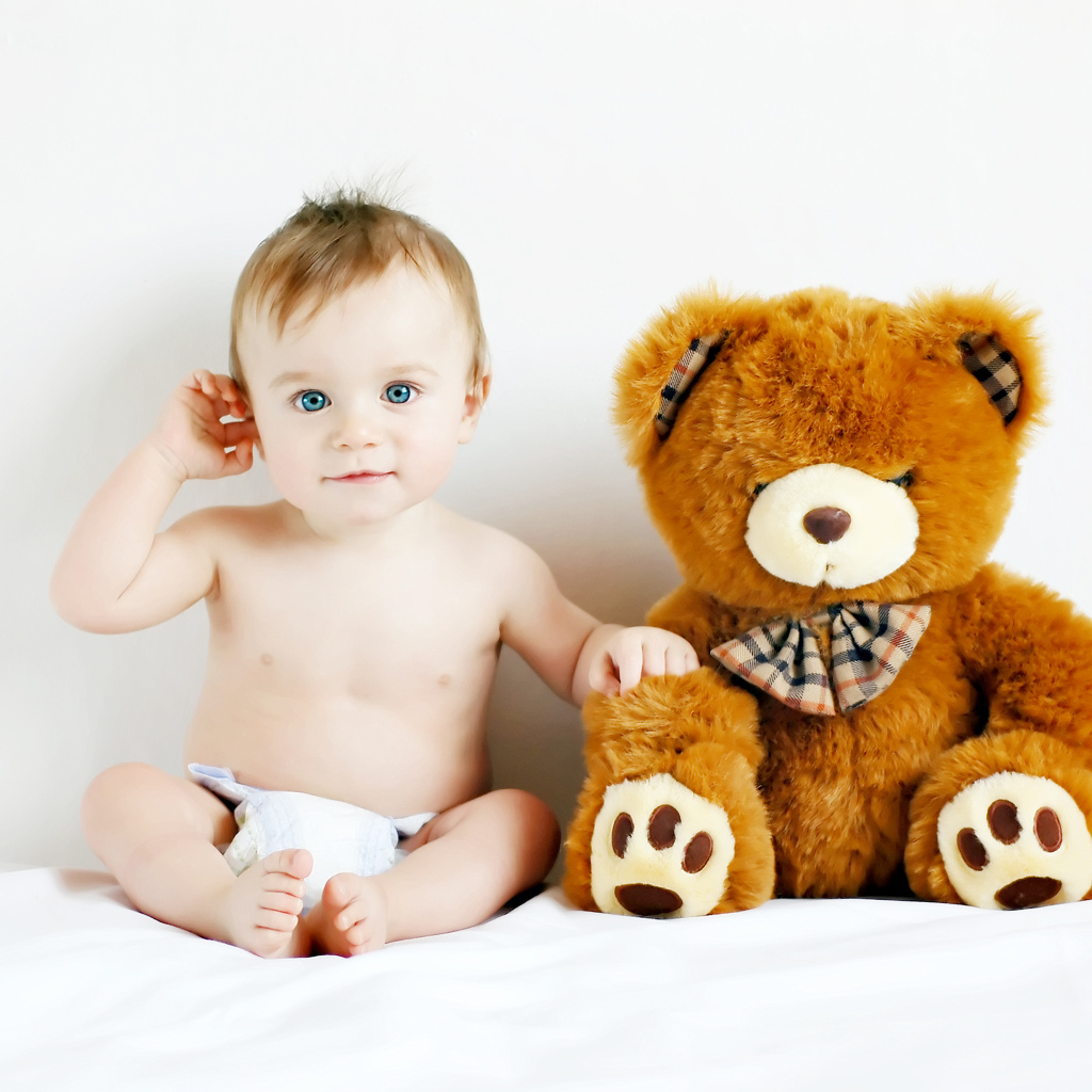 Маленький голубоглазый ребенок с большим плюшевым медведем