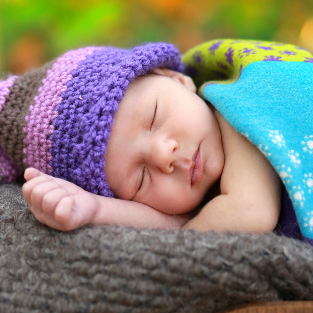 Маленький спящий младенец в вязаной шапке 