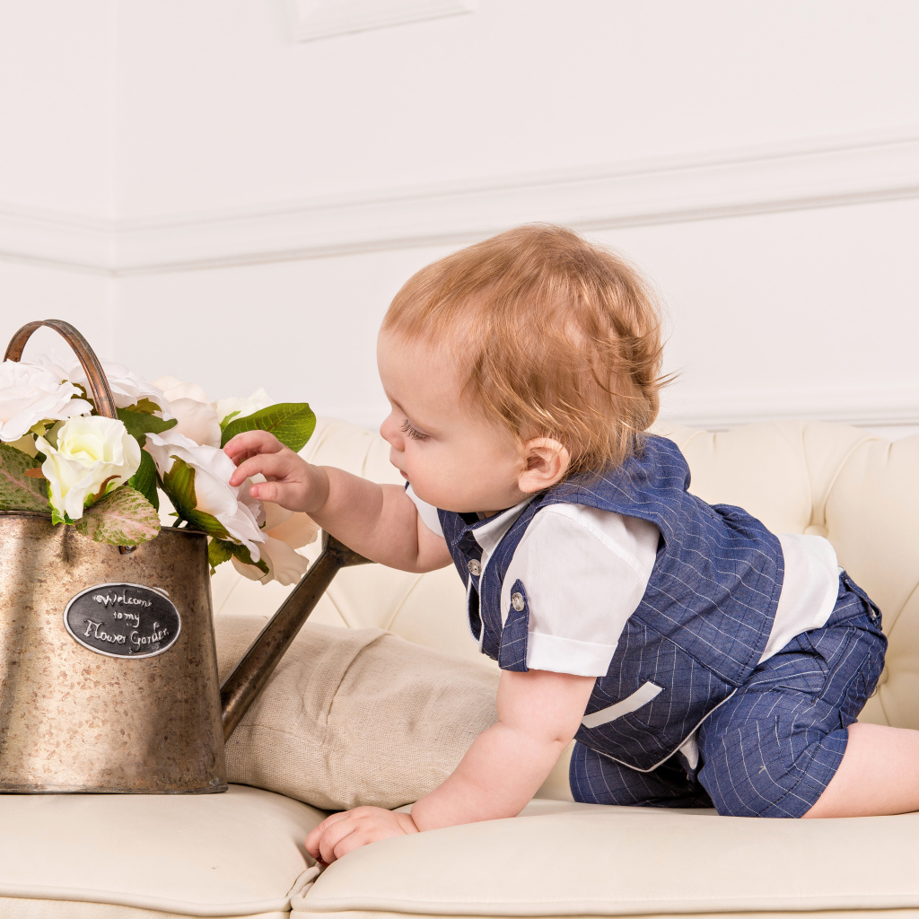 Маленький ребенок рассматривает цветы в железной лейке