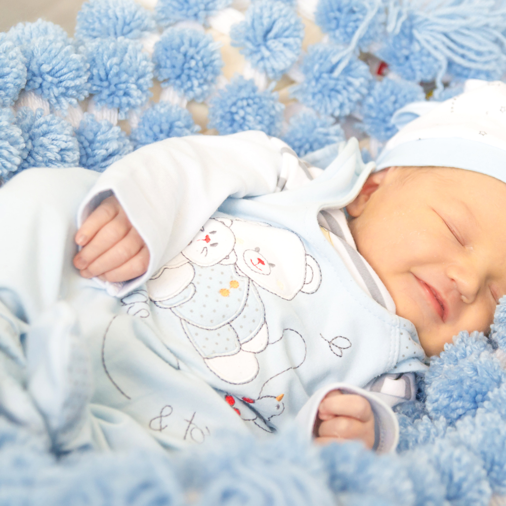 Младенец мальчик улыбается во сне