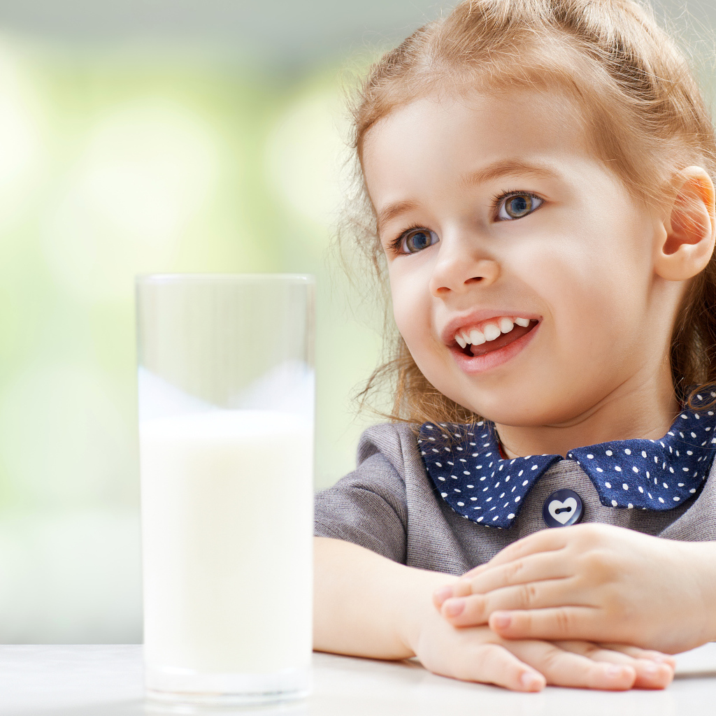 Красивая кареглазая девочка со стаканом молока