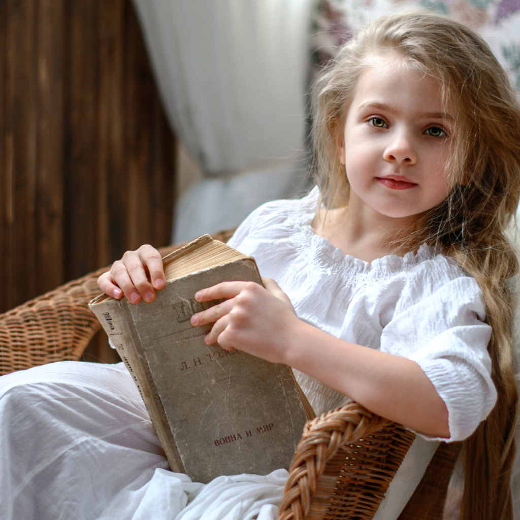 Красивая маленькая девочка в белом платье с книгой 