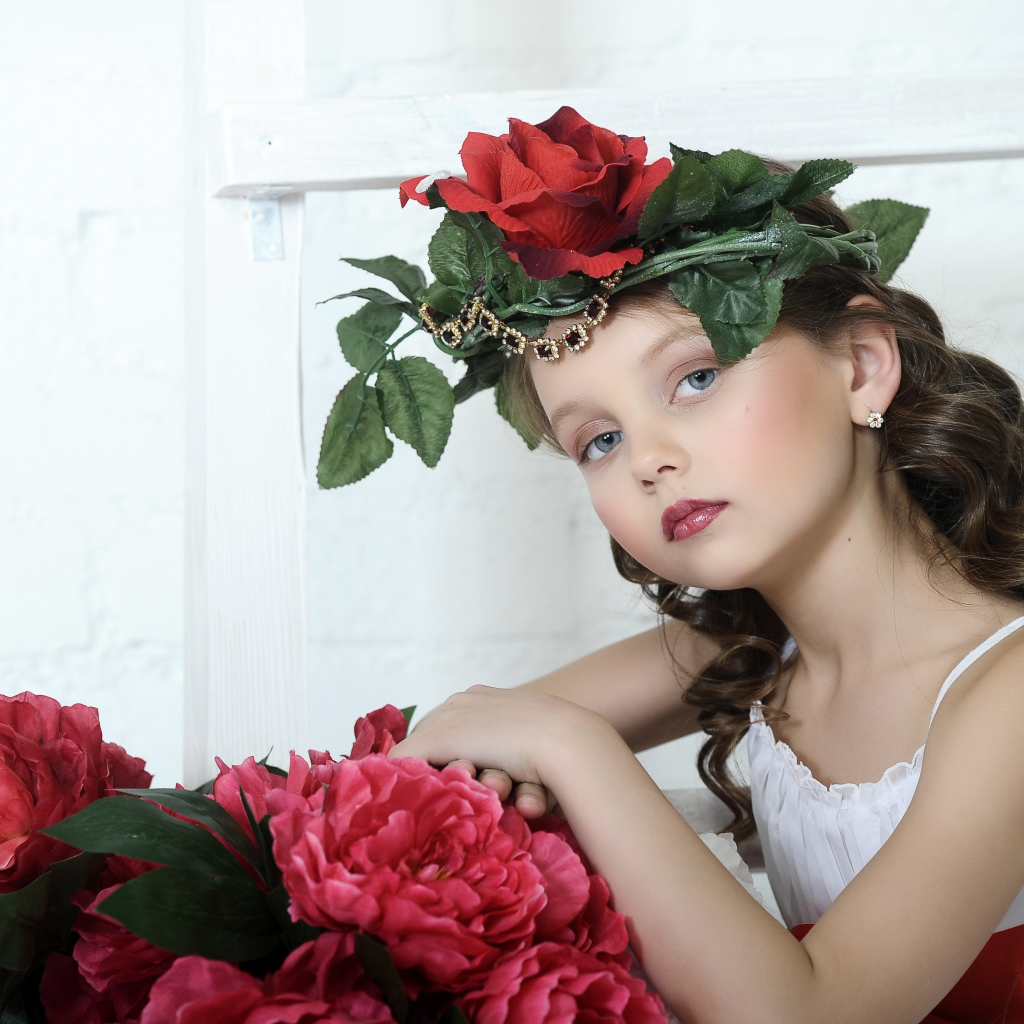 Красивая маленькая девочка с венком из роз на голове