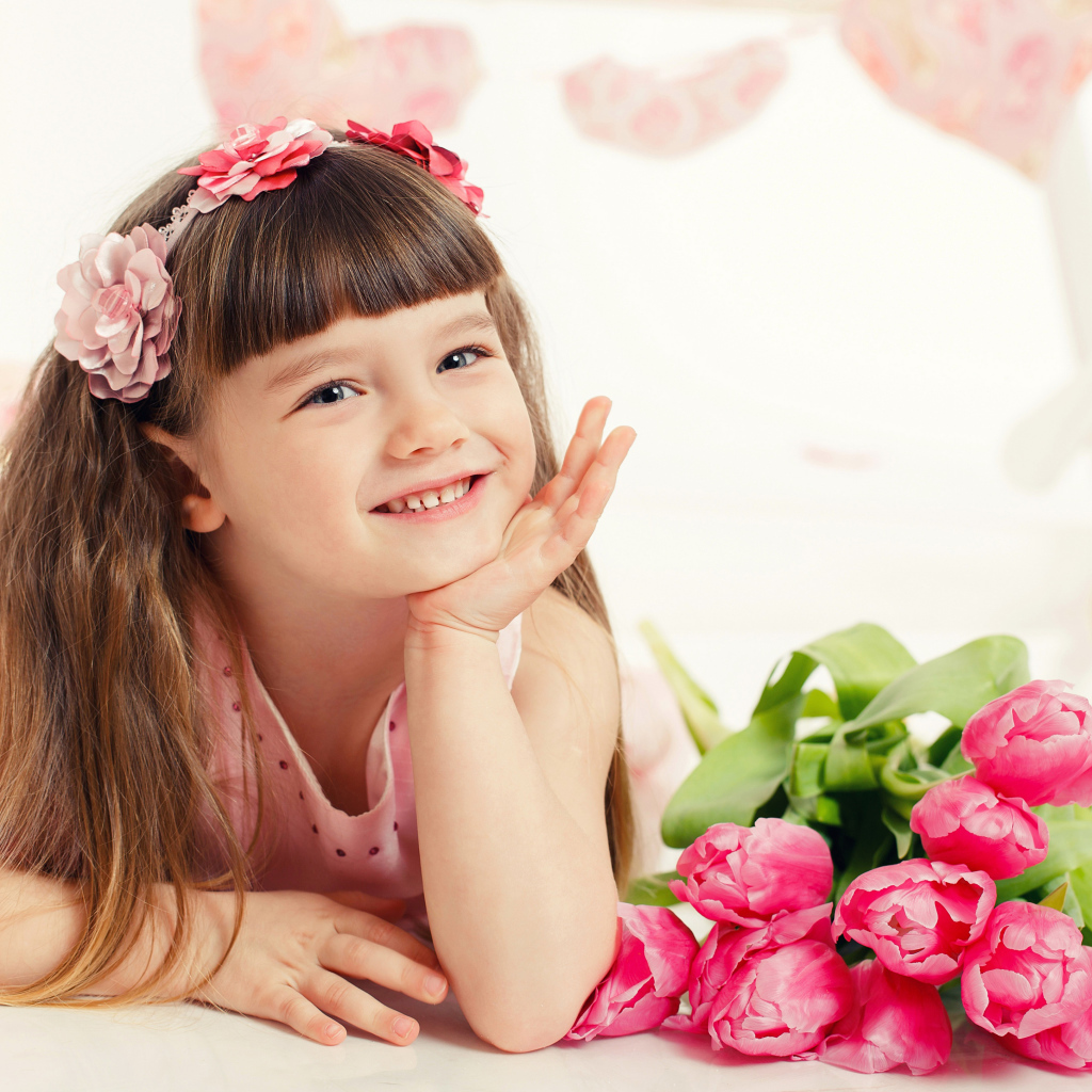 Красивая длинноволосая улыбающаяся девочка с букетом розовых тюльпанов