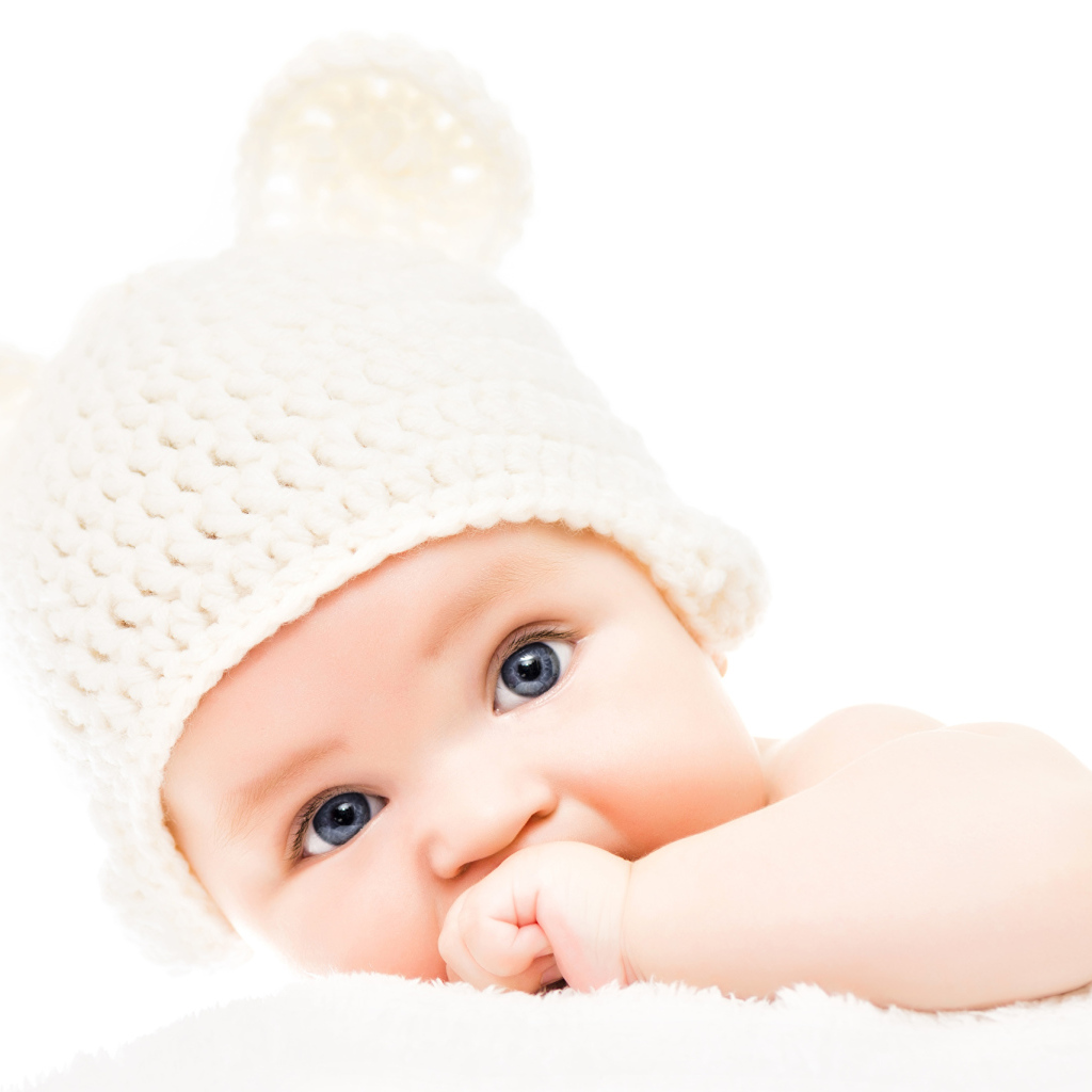Голубоглазый младенец с белой шапке с ушками на белом фоне
