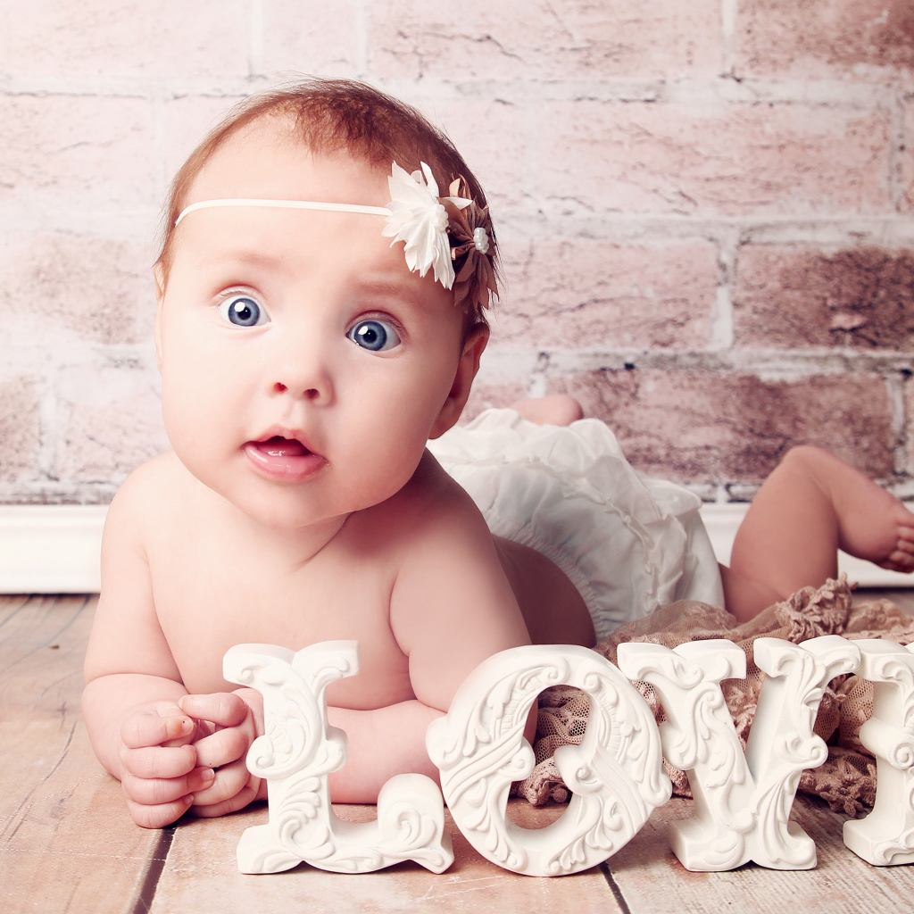 Грудной ребенок с надписью любовь на фоне кирпичной стены