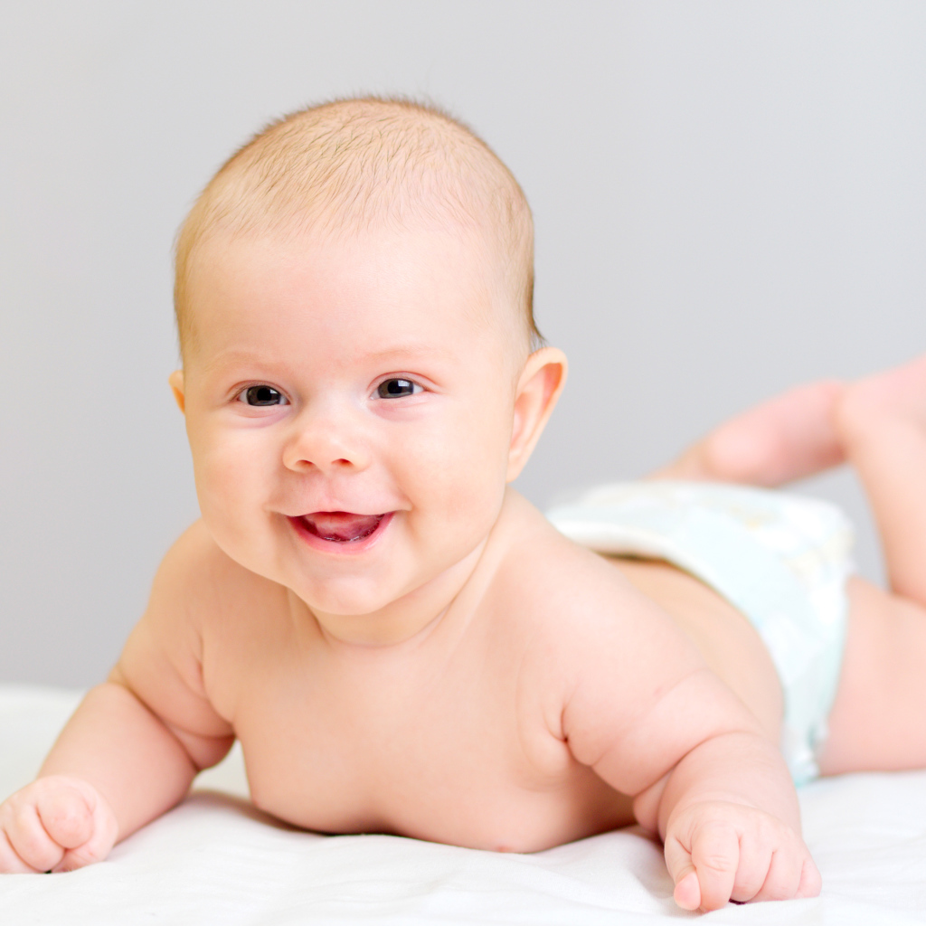 Милый улыбающийся ребенок на сером фоне