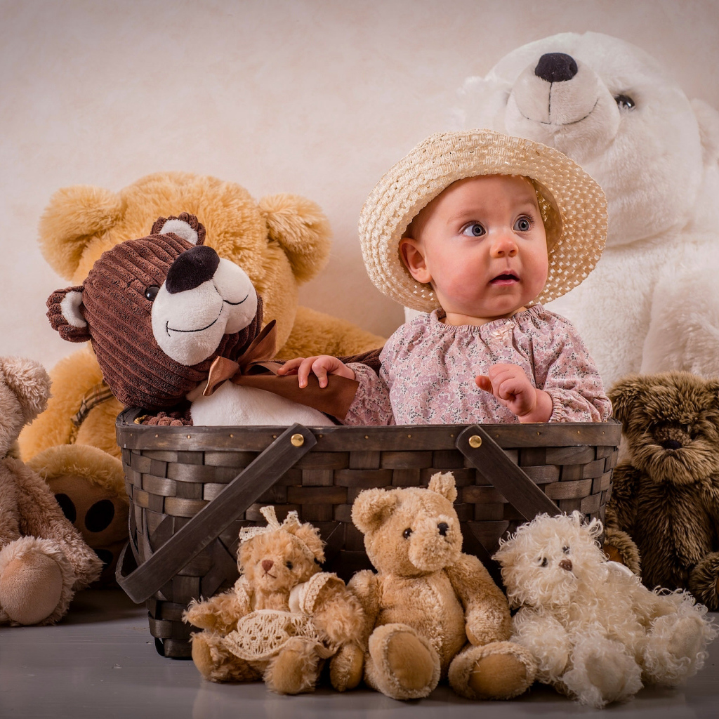 Забавный грудной ребенок в корзине с мягкими игрушками