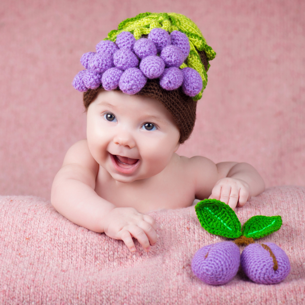 Забавный грудной ребенок в вязаной шапке с ягодами на голове