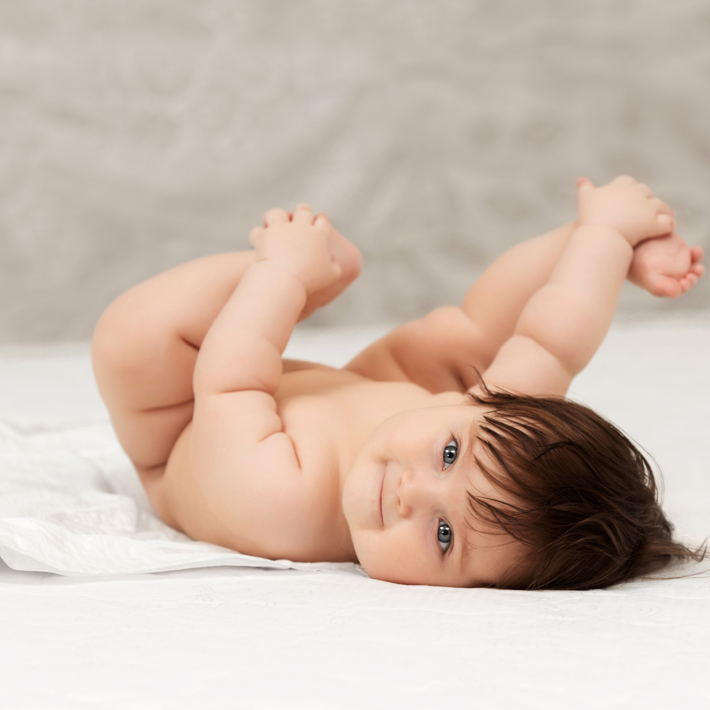 Забавный младенец держится руками за ноги 