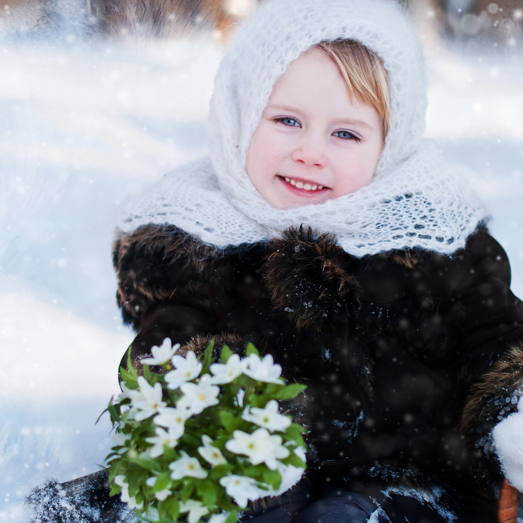 Маленькая голубоглазая девочка с букетом подснежников зимой