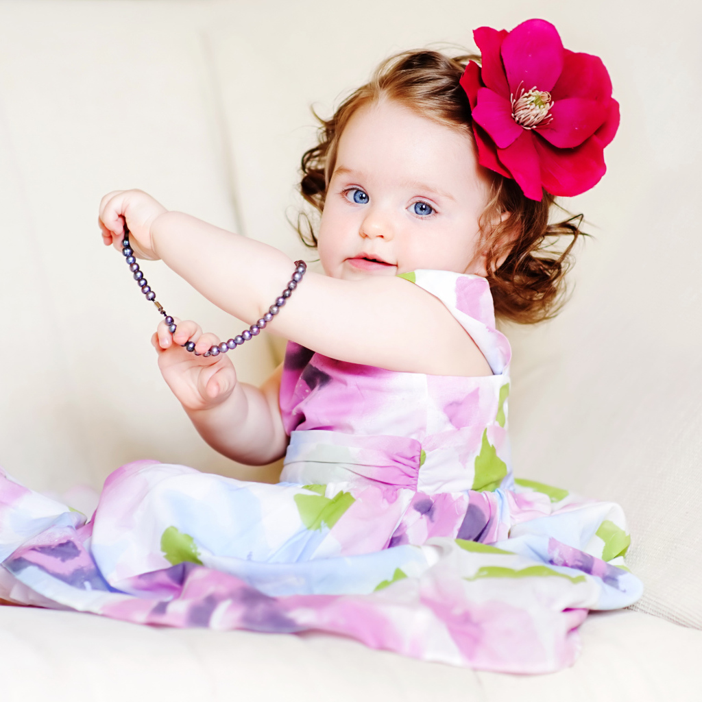 Маленькая голубоглазая девочка с красным цветком в волосах