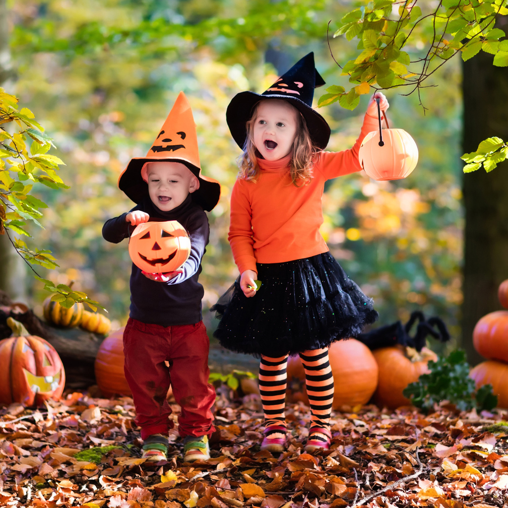 Маленькие мальчик и девочка в костюмах с тыквами на Хэллоуин