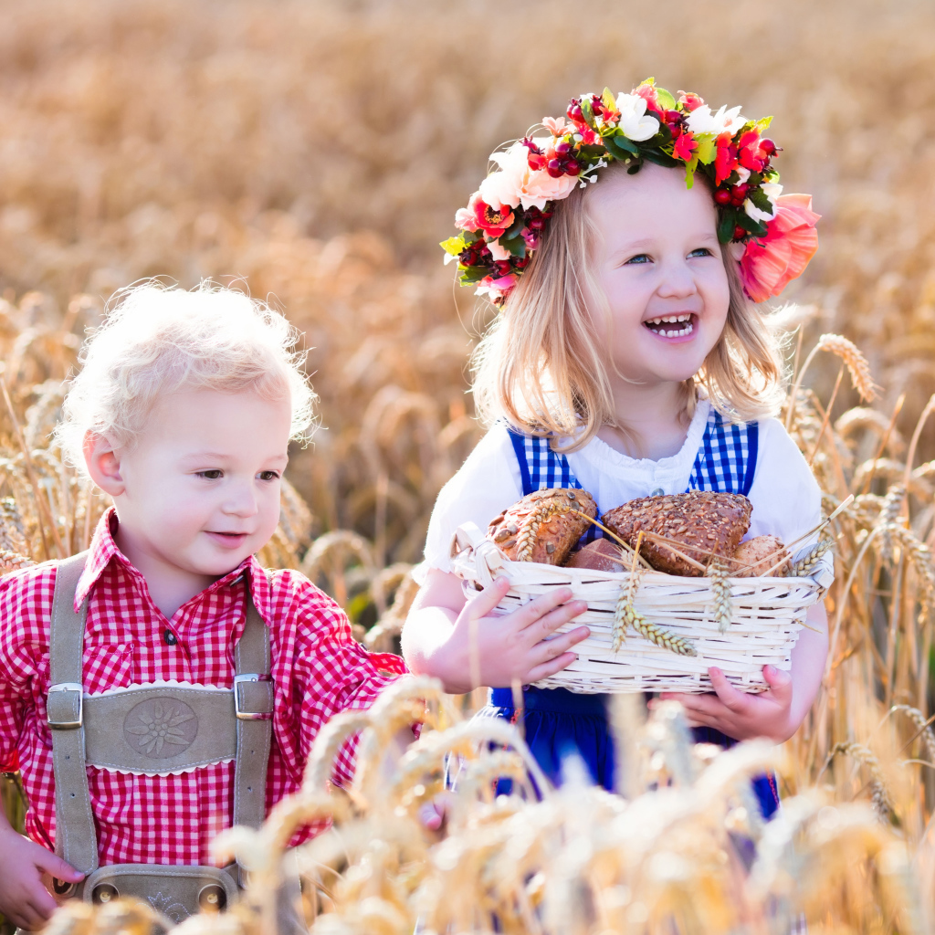 Маленькие мальчик и девочка на поле пшеницы с корзиной свежей выпечки