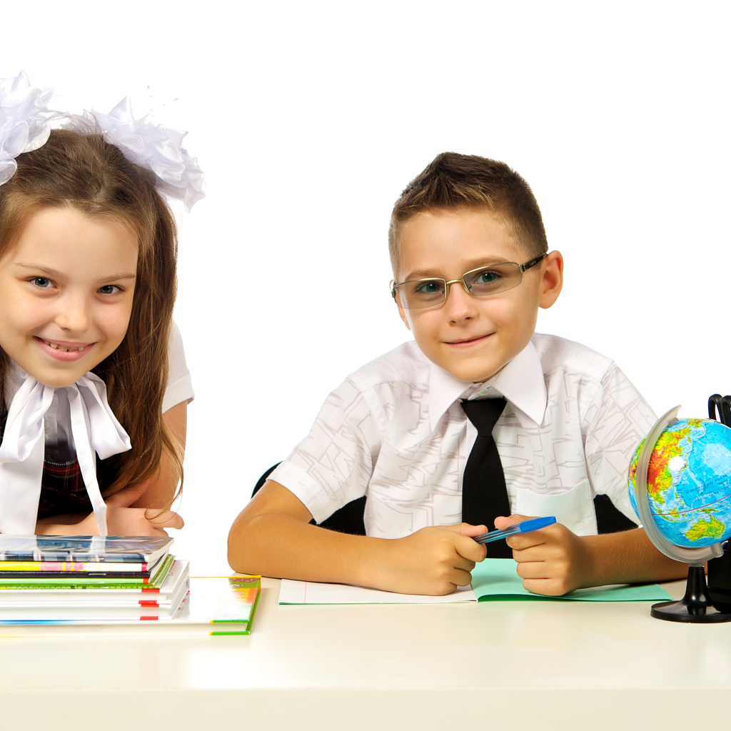 Маленькие мальчик и девочка школьники на белом фоне